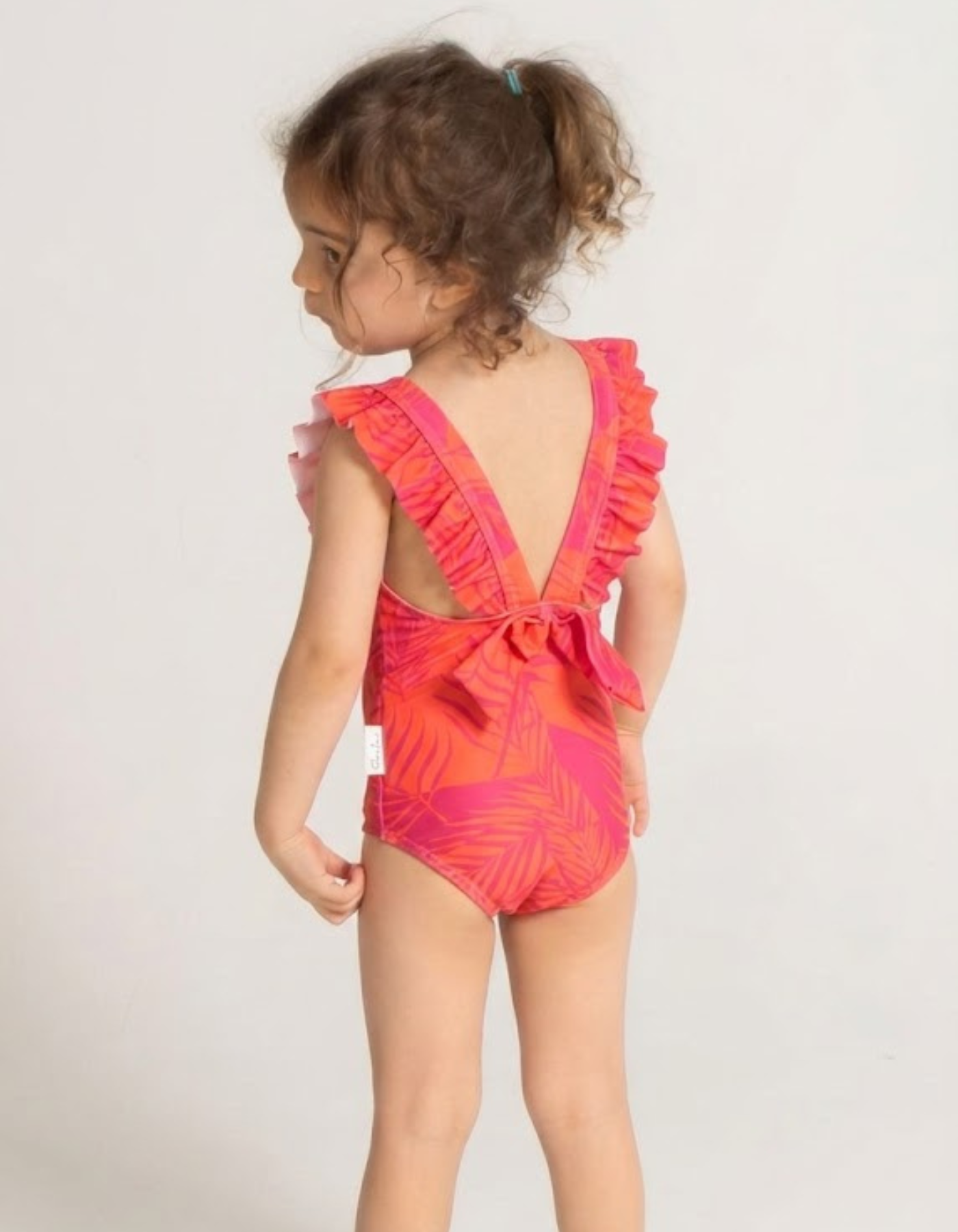 Aperol Palm Girls Ruffle Swimsuit, back view. Sustainable girls swimwear.