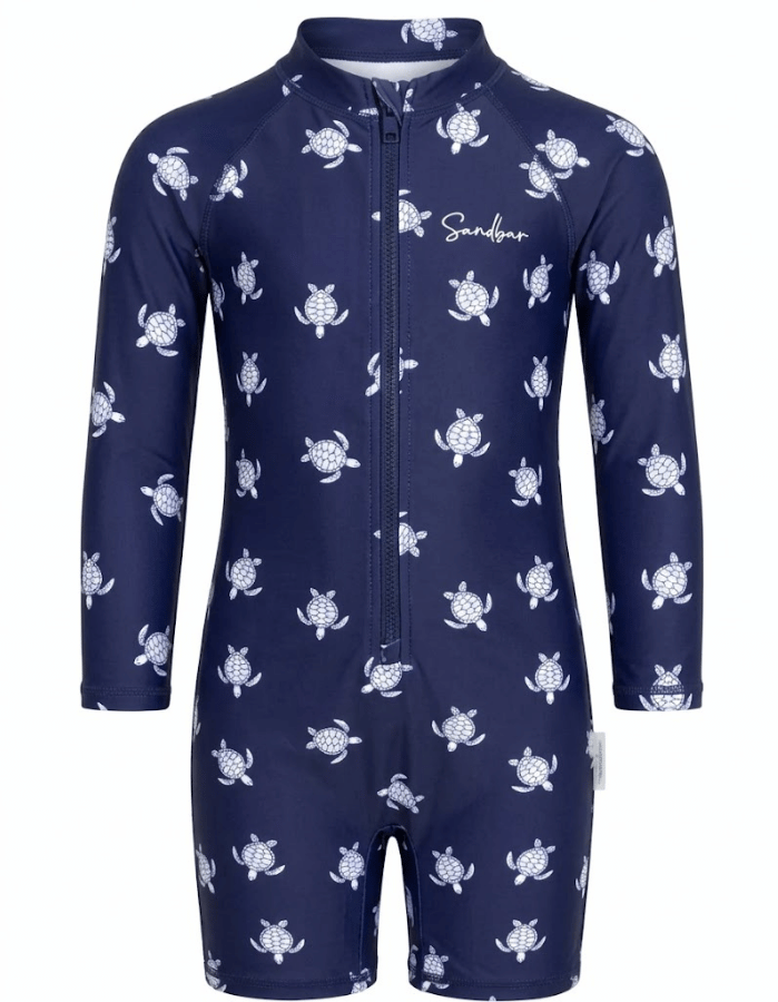 A navy blue long-sleeve baby swim coverall with a white sea turtle pattern, featuring a front zipper and a white 'Sandybar' brand logo on the chest.