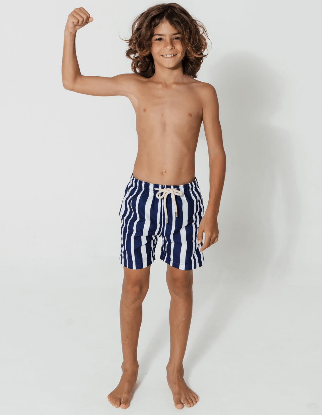 Blue & White Striped Boys Swim Shorts, lifestyle shot. Sustainable boys swimwear.