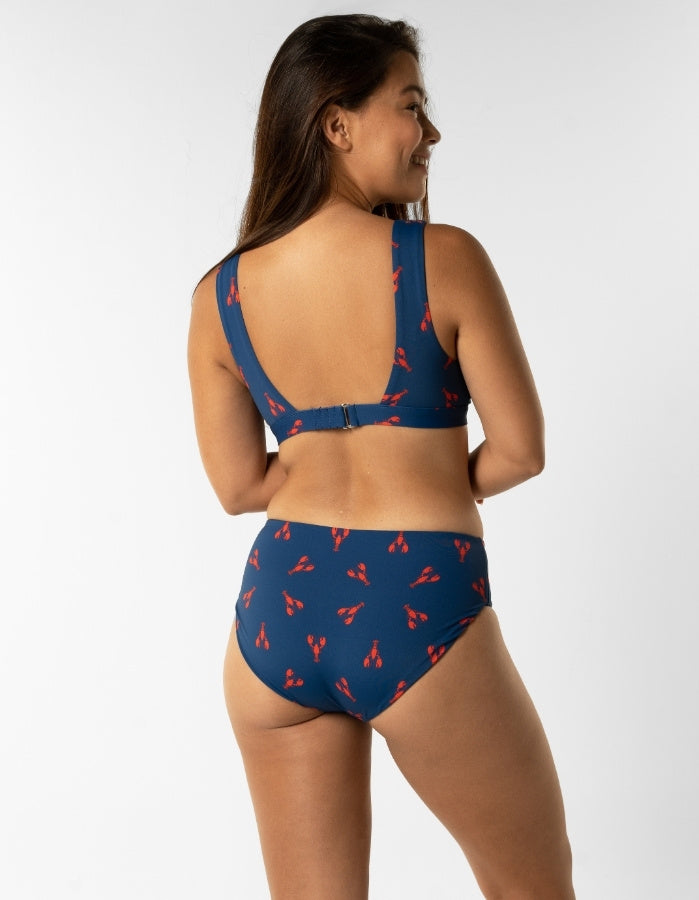 Dune – Royal Red Lobster Womens Plunge Bikini Top, lifestyle shot. Sustainable womens swimwear.