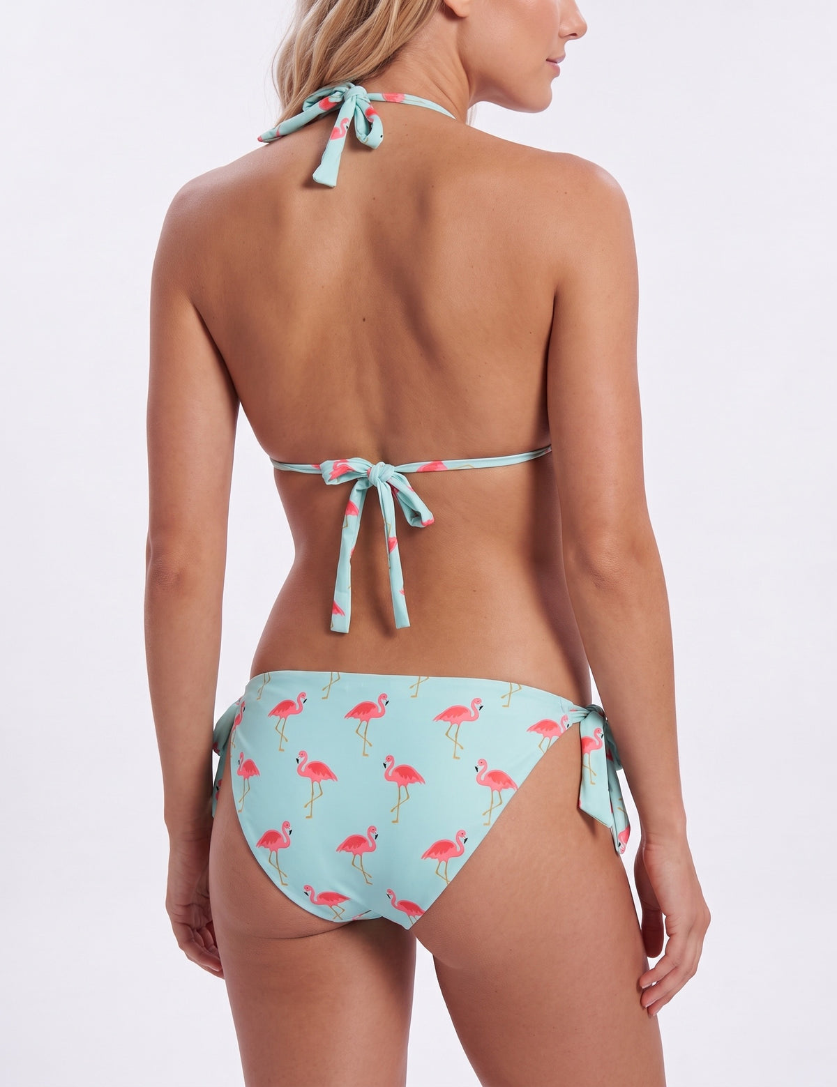 Rear view of a model wearing a light blue string bikini with a pink flamingo print, set against a plain white studio background.