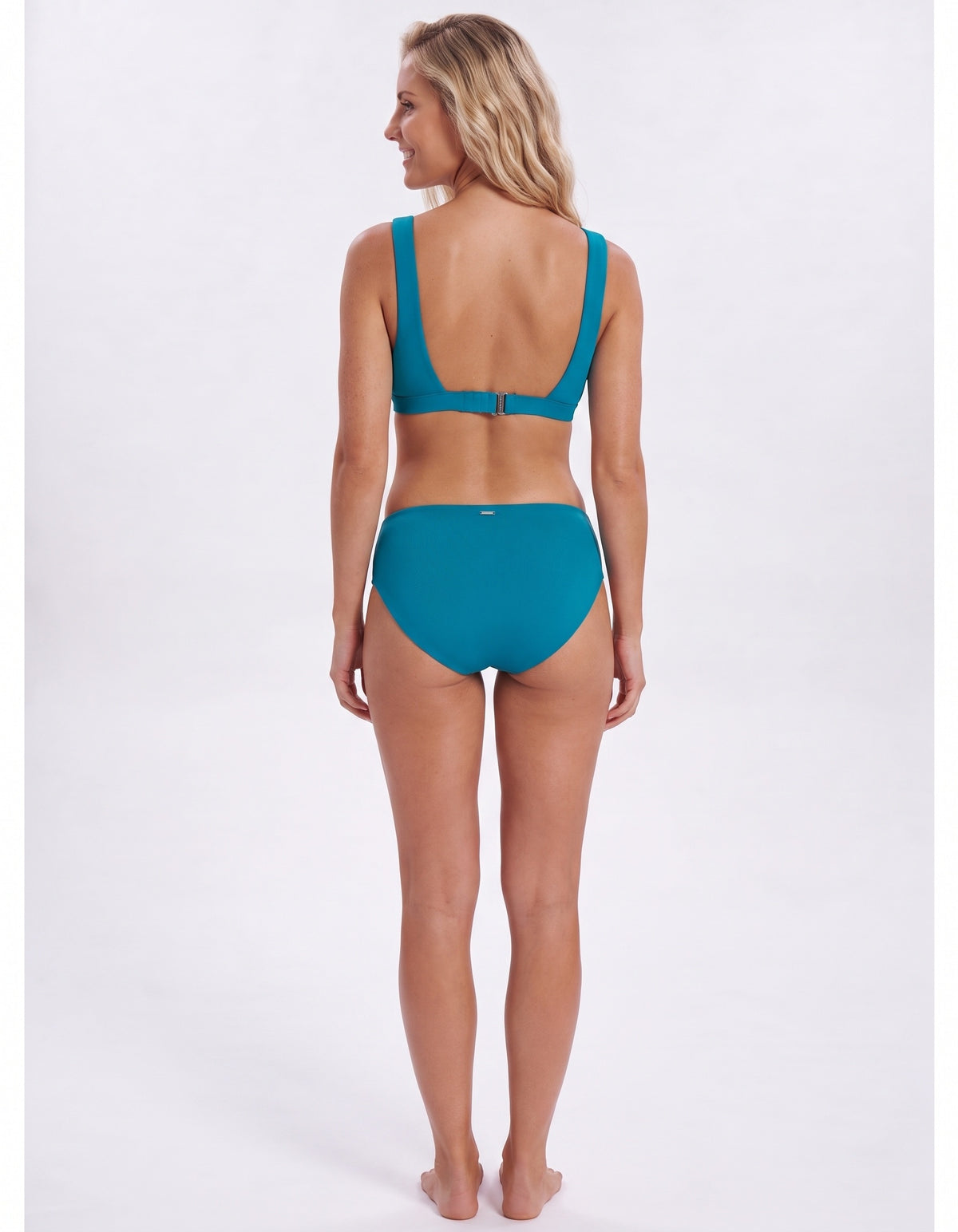 A woman shown from the back wearing a teal two-piece bikini against a plain light gray studio background.