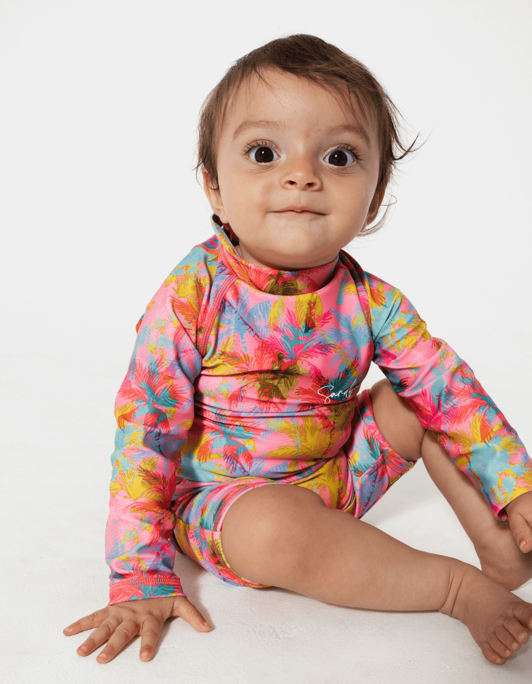 Pink Palm Baby Swimsuit, lifestyle shot. Sustainable baby swimwear.