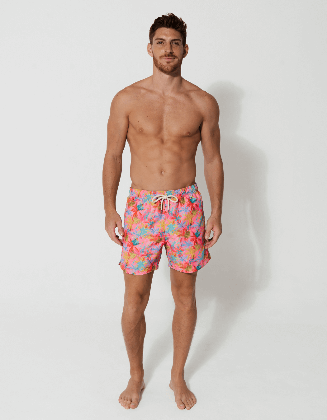 Pink Palm Mens Swim Shorts, lifestyle shot. Sustainable mens swimwear.