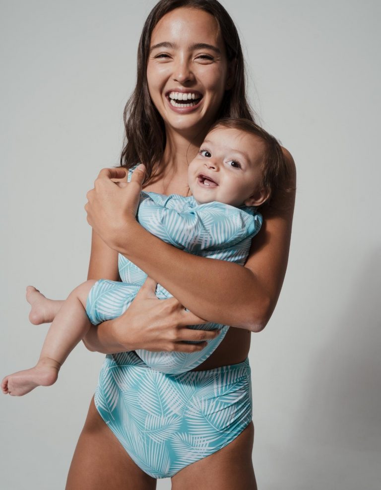 Mother holding her baby, both wearing Sandbar swimwear
