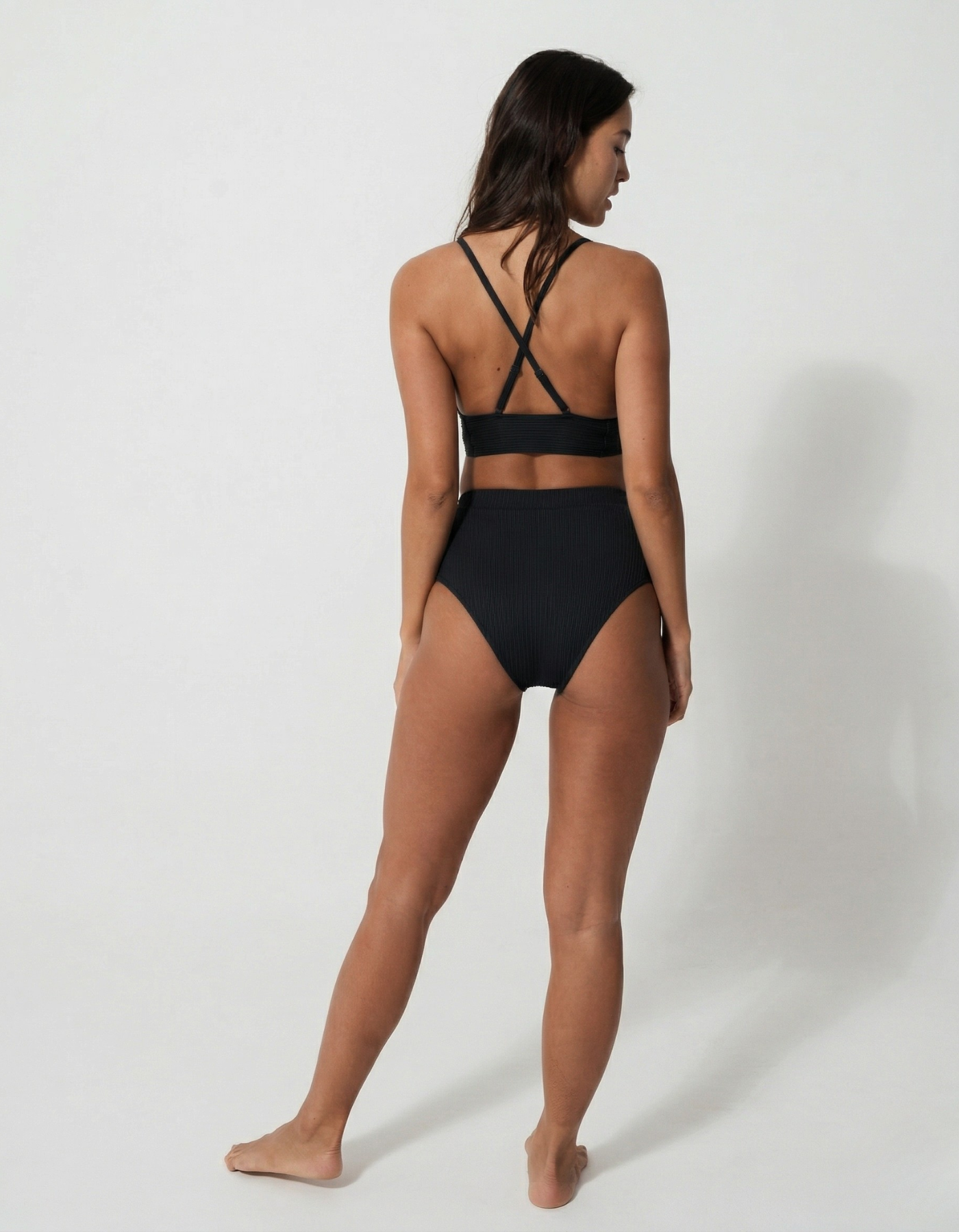 Flores Black Womens Ribbed Plunge Bikini Top, lifestyle shot. Sustainable womens swimwear.