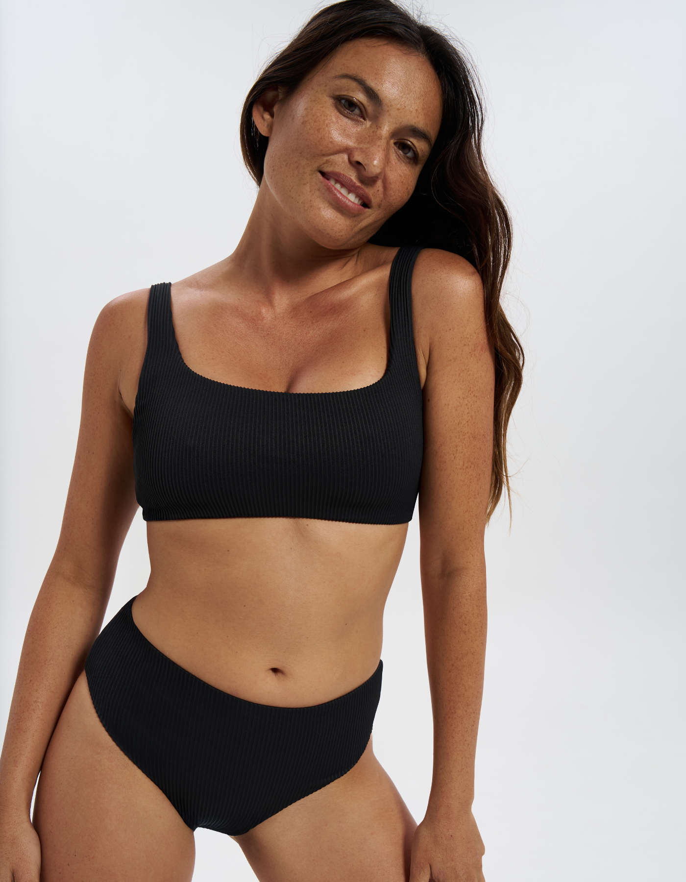 Nikoi Black Womens Ribbed Tank Bikini Top, lifestyle shot. Sustainable womens swimwear.
