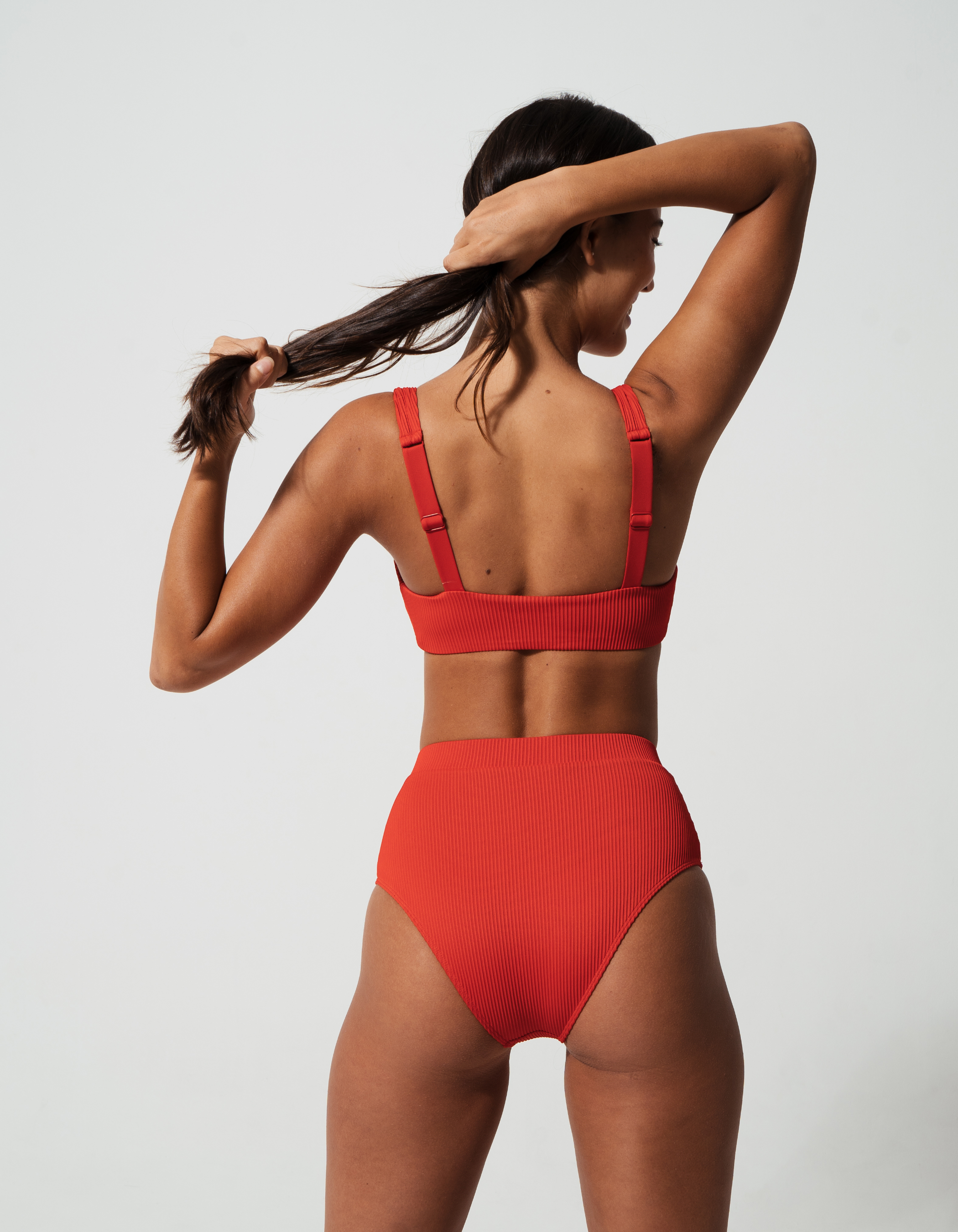 Nikoi Lipstick Red Womens Ribbed Tank Bikini Top, lifestyle shot. Sustainable womens swimwear.