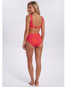 A woman modeling a two-piece bikini swimsuit from the back, featuring a bright coral pink and orange tropical leaf pattern, set against a plain light gray studio background. Sandbar Swimwear