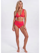 A woman modeling a two-piece bikini set with a vibrant orange and pink abstract pattern, standing against a plain light gray studio background. Sandbar Swimwear