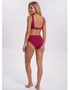 A woman modeling a two-piece bikini from the back, featuring a deep scoop neck and high-waisted bottoms, in a solid deep magenta color, set against a plain light gray studio background. Sandbar Swimwear