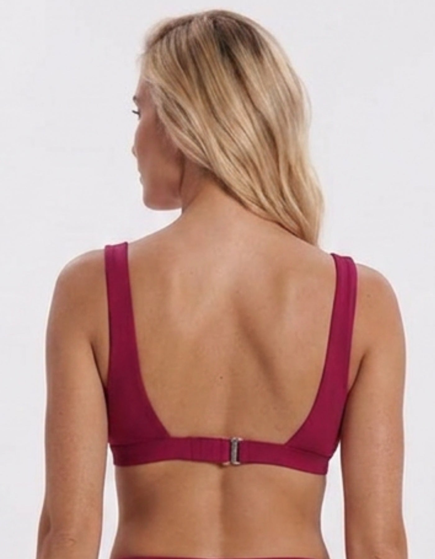 A woman shown from the back wearing a deep magenta-burgundy bikini top with a wide strap design and a small silver buckle at the center of the waistband, against a plain light gray background.Sandbar Swimwear