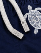Embroidered Turtle Boys Swim Shorts, front view. Embroidered kids swim shorts metal string end caps