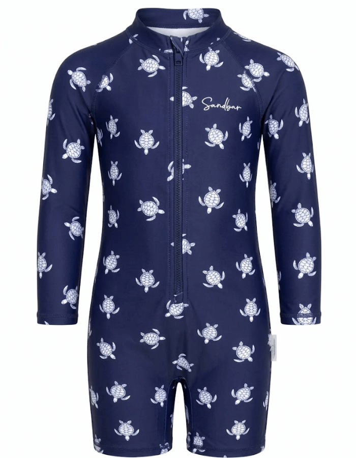 A navy blue long-sleeve baby swim coverall with a white sea turtle pattern, featuring a front zipper and a white 'Sandybar' brand logo on the chest.