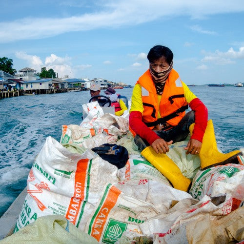 Seven Clean Seas crew in a boat with sacks of plastic recovered from the water