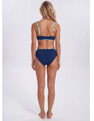 A woman shown from the back wearing a two-piece bikini. The bottom is solid navy blue, while the top has a tropical leaf print with green, yellow, and blue on a white base. Sandbar Swimwear