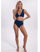 A woman modeling a two-piece navy blue bikini against a plain light gray studio background. Sandbar Swimwear