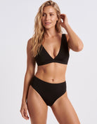 Woman wearing Mid Waist Black bikini bottoms with the black plunge top, front view