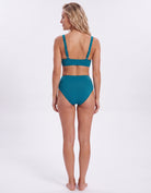 A woman modeling a teal two-piece bikini from the back, standing against a plain white studio background.